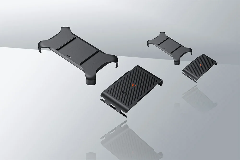Four pieces of black holder and cover for the device spread out over a mirrored bright surface