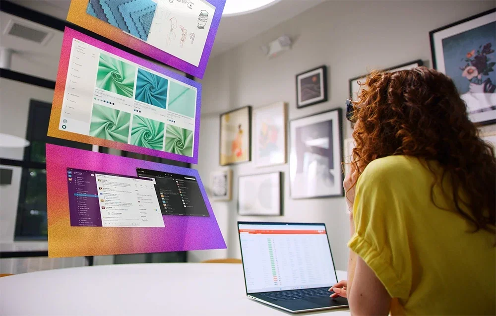 Moteris dirba prie stalo su nešiojamuoju kompiuteriu ir XR akiniais