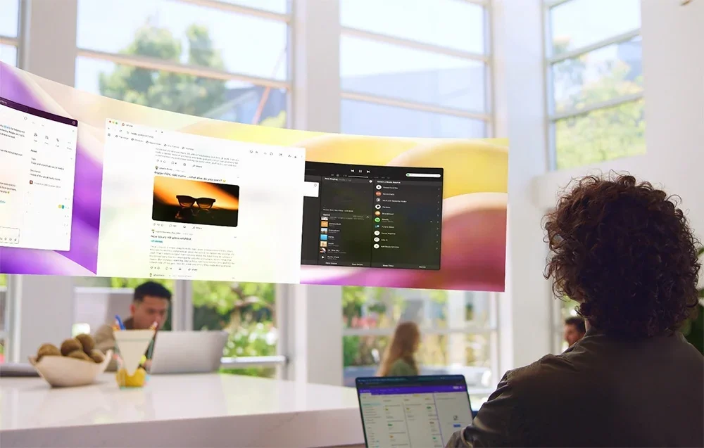 Žmogus žiūri į virtualius ekranus su XR akiniais šviesiame kambaryje