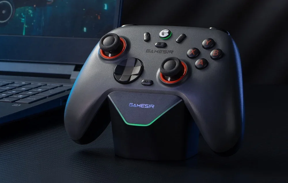 Dark gray GameSir controller with red backlight placed on docking station in front of laptop.