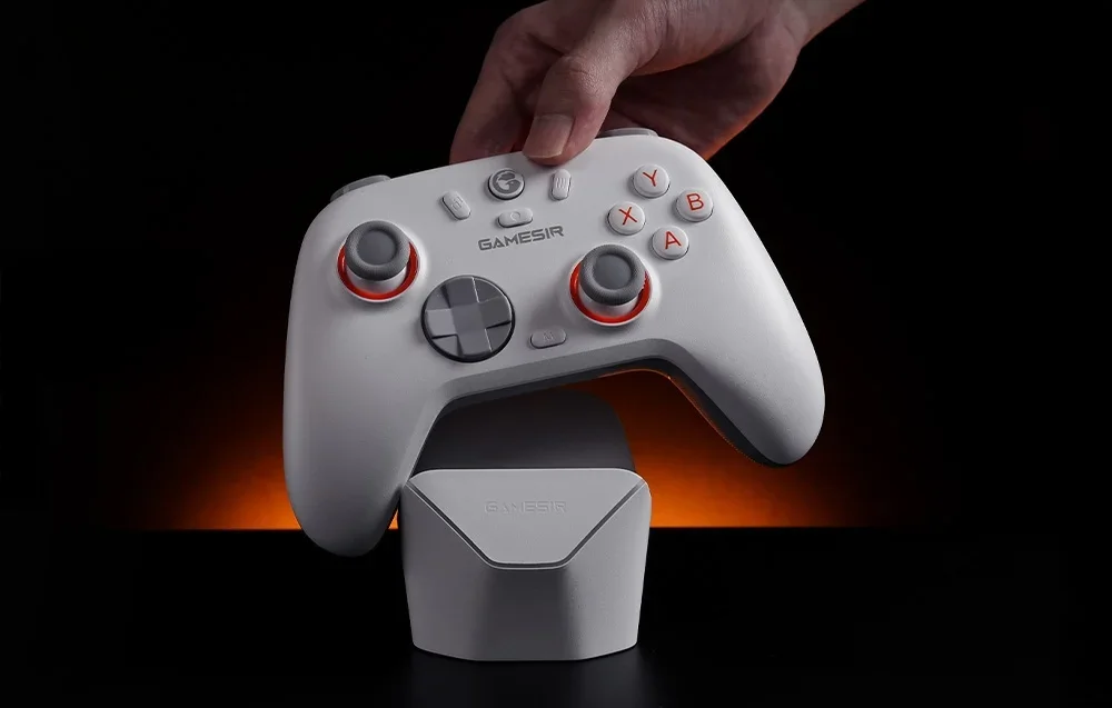 White GameSir controller with red backlight held above the docking station against a dark background.