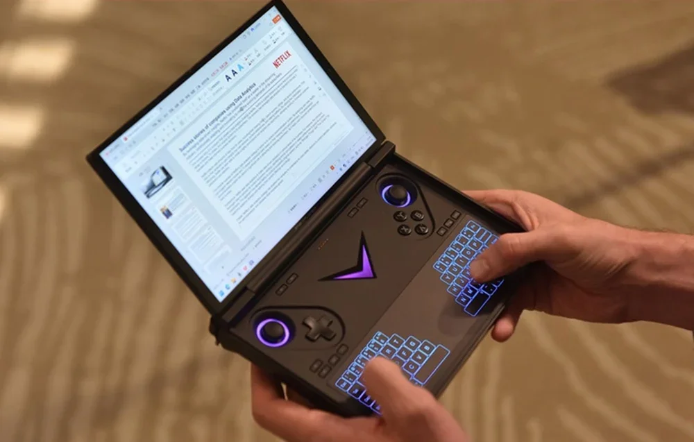 Hands hold a foldable gaming console with two screens, one showing a document, the other with controllers and backlighting