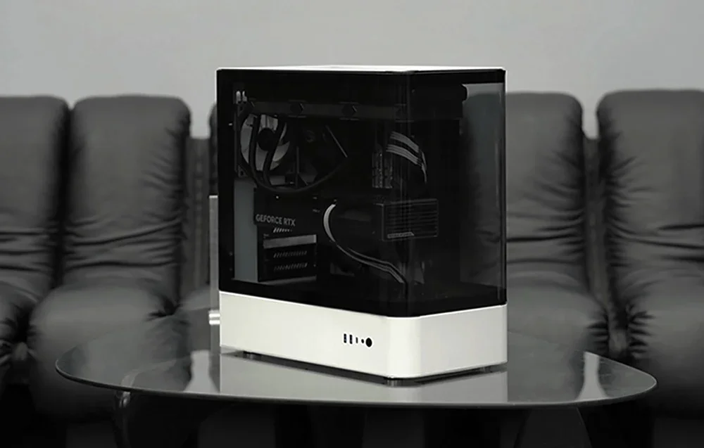 White-black computer case on dark table, black couch in the background