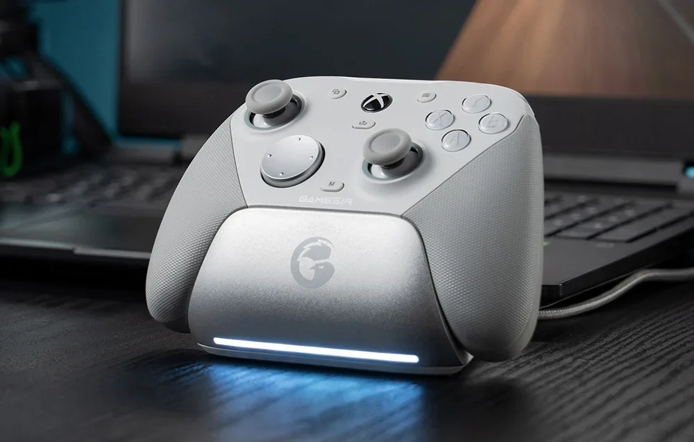 Baltas GameSir valdiklis įkrovimo stotelėje priešais nešiojamąjį kompiuterį.