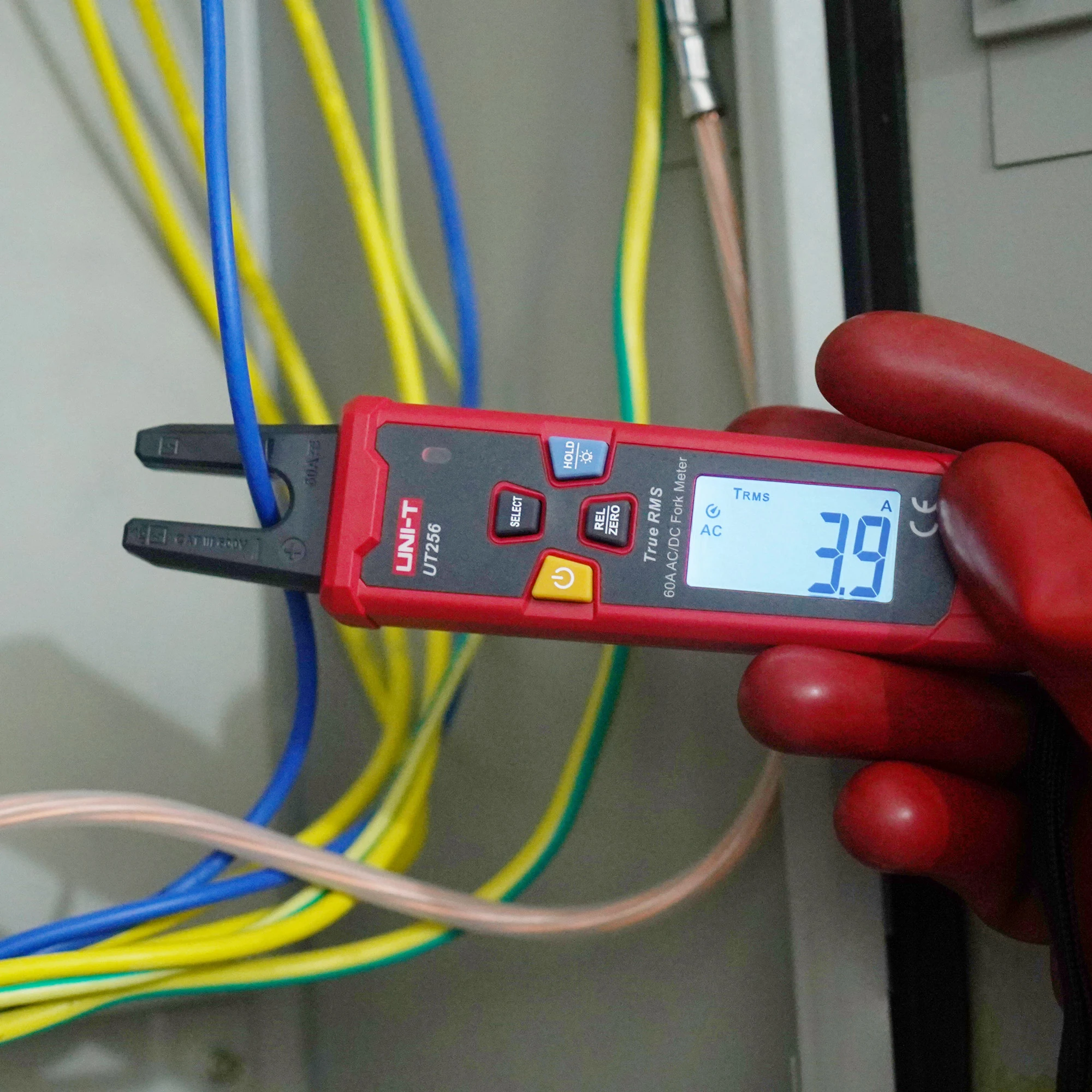 UNI-T UT256 pirštinėta ranka laiko šalia spalvotų laidų